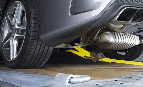 Two Inch Wide By Thirty Six Inch Long Premium Axle Tie Down Strap With D Rings securing vehicle on trailer