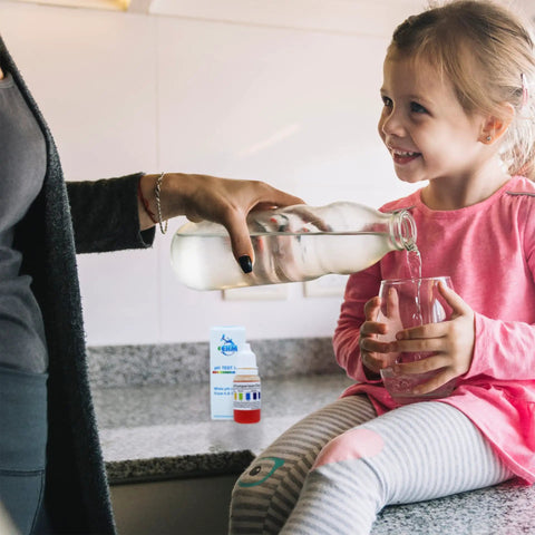 Dead Nuts Accurate Alkaline Water pH Test Kit For Drinking Liquids Delivers Knockout Precision in a kitchen while pouring water into a glass.