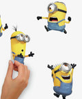 Person applying Minions The Rise Of Gru Peel And Stick Vinyl Wall Decals Set Of 30 for kids rooms, repositionable on surfaces.