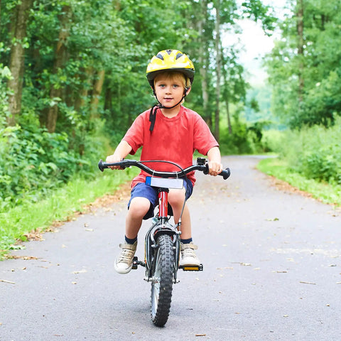 Child riding a bike in park wearing red shirt and yellow helmet, showcasing Two Pack 14 Inch Bike Tubes Heavy Duty 14x2.10 To 14x2.50 AV32mm
