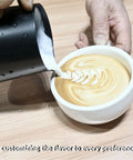 Latte art being poured into a white cup on a wooden surface, showcasing a barista's skill with Two Group Commercial Espresso Machine With Semi Automatic Controls 1.6 Gallon Boiler Rotary Pump Stainless Steel Finish Pro Grade Boss Level Coffee Shop Power For Busy Cafes And Restaurants.