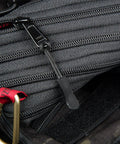 Black zipper with durable non-slip PU grip zipper pull tab extension attached to gray backpack.