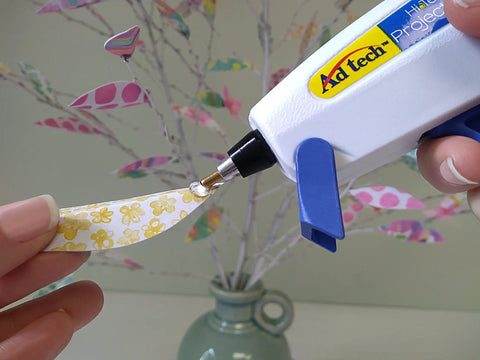 Person using glue gun with 8-Inch Clear Mini Hot Glue Sticks For Crafting And DIY Projects, Multi-Temp Bond on paper decoration.