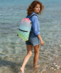 Woman at beach with Colorful Fish Feather Drawstring Backpack Sackpack for Gym and Everyday Use, lightweight polyester bag, side view.