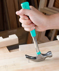 8 Oz Claw Hammer With Shock Reduction And Non Slip Grip Turquoise Handle For Home And Professional Use Durable Steel Construction Flat Head With Nail Puller And Prying Claw Comfort Grip That Reduces Vibration For Less Fatigue being used to remove a nail from wood