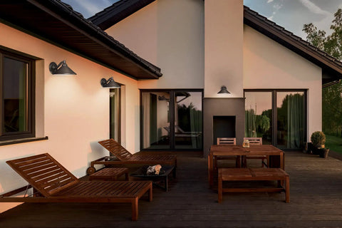 Go To Outdoor Wall Light In Bronze Aluminum Dark Sky Exterior Lantern illuminating a patio with lounge chairs and table