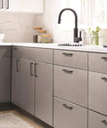 Modern kitchen featuring Matte Black Revolve Cabinet Pull 5-1/16 Inch Center To Center installed on gray cabinets and drawers.