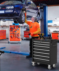 7 Drawer Rolling Tool Chest With Locking System On Wheels, Beefy High Capacity Steel Tool Cabinet For Garage, Workshop, And Warehouse, Durable Black Metal Storage Cart beside mechanic in auto shop