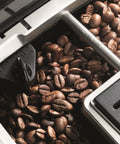 Fully Automatic Espresso And Cappuccino Maker With Precision Burr Grinder For Smooth Milk Frothing And Solid Stainless Steel Cabinet Profile showcasing roasted coffee beans in grinder compartment.