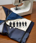 6 Piece Zipper Restoration Kit With Metal Sliders And Teeth, Universal Repair Set for jackets, bags, luggage next to sewing machine