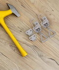 Two Pack Tough As Nails Heavy Duty Stainless Steel Toggle Clamp Latch With Lock Hole Design next to yellow hammer on wood surface