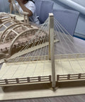 Detailed view of wooden bridge model with cables on a tabletop, ideal for DIY craft projects.