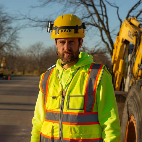Worker wearing yellow helmet with Helmet Strap Mount Accessory With Two Magnetic Mounts And Screw In Feature for hard hats.