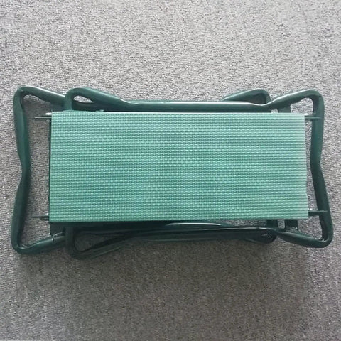 Garden Kneeler And Seat Heavy Duty Portable Folding Bench, shown folded, with green cushioned pad on carpet surface.