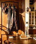 Top Shelf Matte Black Wall Coat Hooks Four Pack holding a brown jacket and scarf on a wooden door in a cozy room.