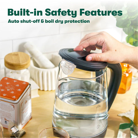 Person using 1.7 Liter Glass Electric Kettle That Boils Seven Cups In Just Six To Seven Minutes With Soft Blue LED Lights, Black Finish.