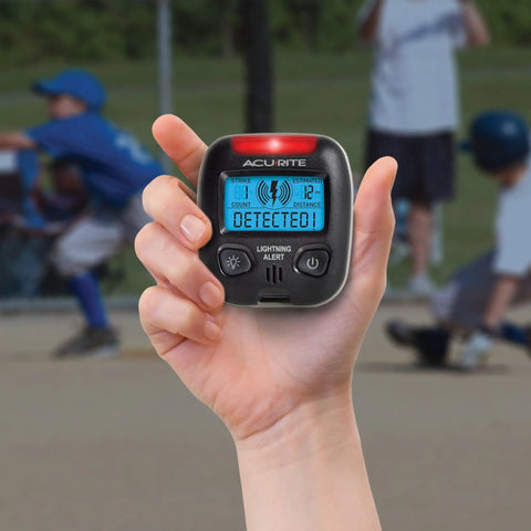 Hand holding Portable Lightning Detector With 25 Mile Storm Alert Audible Alarm Text Alerts Strike Counter Estimated Distance To Storm And Backlit Display For Easy Night Viewing.