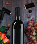 200 Piece Black Heat Shrink Wine Bottle Caps With Tear Tab 30Mm By 60Mm Pvc Shrink Sleeve Seals For Home Cellar, displayed on wooden surface with wine bottle and grapes.