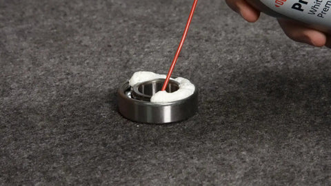 Applying Teflon White Lithium Grease Aerosol Spray 10 Oz for all weather lubrication on a bearing, low odor, resists heat and cold.