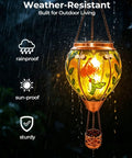 Glass Hot Air Balloon Solar Lantern With Flame Hand Painted Artwork Realistic Flickering Flame Hummingbird Accent Rustproof Metal Outdoor Solar Light For Garden Or Yard Easy Setup And Eco Friendly illuminated in the rain, showcasing weather resistance.