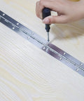 Installing Tough as Nails Heavy Duty 12 Inch Stainless Steel Piano Hinges 4 Pack With 48 Screws on wooden surface with screwdriver