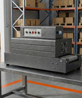 AOXHUGB Electric Heat Shrink Tunnel Machine With Heavy Mesh Conveyor Belt For Square Packaging, side view on a table.