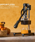Cast Iron Manual Citrus Juicer Heavy Duty Orange Press with basket of oranges and fresh juice glass on kitchen counter.