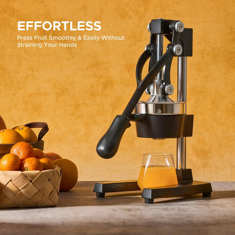 Cast Iron Manual Citrus Juicer Heavy Duty Orange Press with basket of oranges and fresh juice glass on kitchen counter.