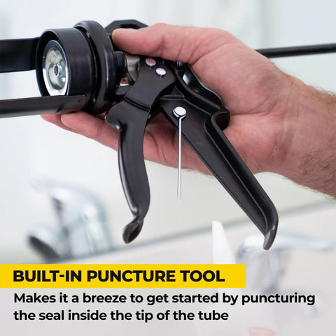 Close-up of black Heavy Duty Caulk Gun 29 Oz No Drip Design with a visible puncture tool in hand demonstrating use