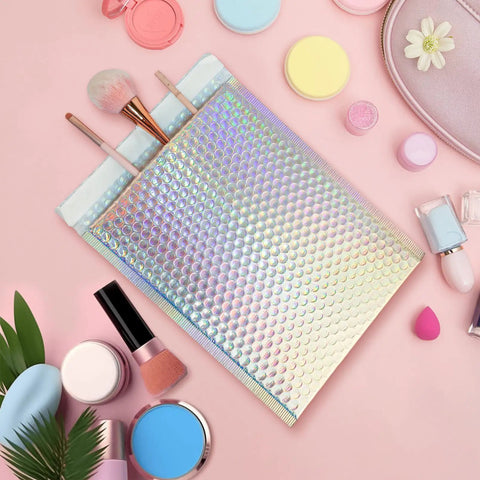 50 Pack Holographic Bubble Mailers Self Seal Waterproof Poly Padded Envelopes on pink background with cosmetics