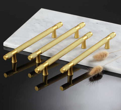 Ten Pack Gold Knurled Cabinet Pulls With 5 Inch Hole Centers 7 Inch Overall Length Brushed Brass Handles arranged on marble