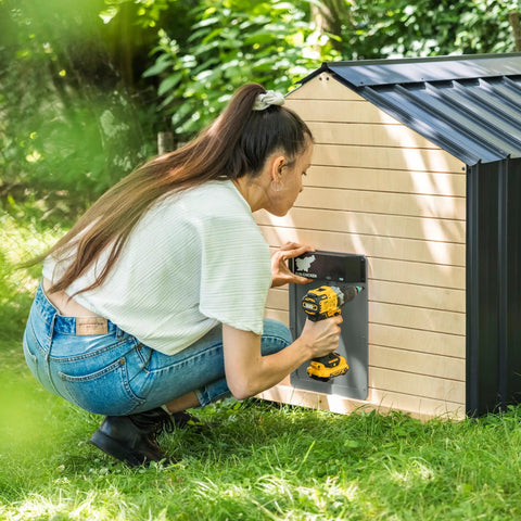 Woman installing Automatic Chicken Coop Door Opener With Battery Power Weatherproof Aluminum Build Smart App And Timer Control Predator Proof Easy