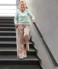 Wall Mounted Stair Handrail Crafted From Premium Stainless Steel Featuring A Sleek Black Square Profile Built Like A Tank For Indoor Spaces Loaded With Rock Solid Grip And Holds Down Weighty Loads Up To Two Hundred Pounds Safely, supporting a person on stairs.