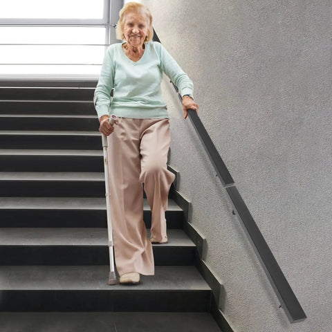Wall Mounted Stair Handrail Crafted From Premium Stainless Steel Featuring A Sleek Black Square Profile Built Like A Tank For Indoor Spaces Loaded With Rock Solid Grip And Holds Down Weighty Loads Up To Two Hundred Pounds Safely, supporting a person on stairs.