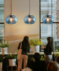 Stylish Hand Blown Glass Pendant Lights For Kitchen Island In Blue Marble Finish above a dining area with flowers.
