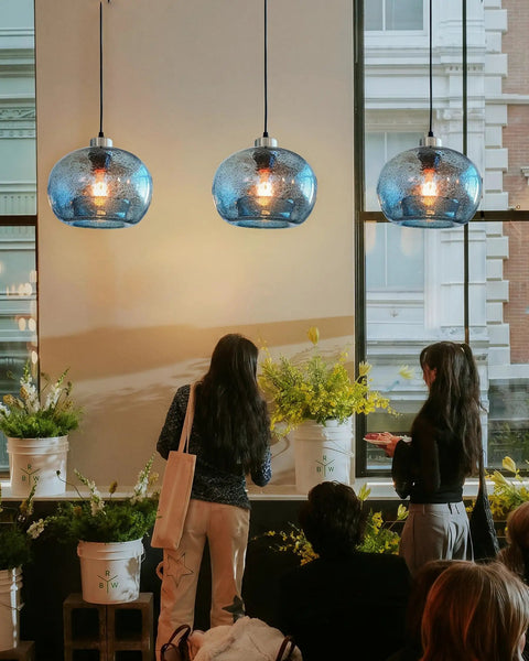 Stylish Hand Blown Glass Pendant Lights For Kitchen Island In Blue Marble Finish above a dining area with flowers.