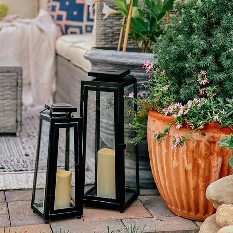 Outdoor Solar Lanterns With Flameless Candles Two Pack 11 Inch Tall Black Metal Glass Lanterns For Patio beside potted plants