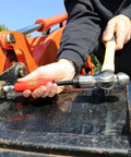 Grease Buster by LockNLube, red-handle tool used to flush old grease from fittings on orange equipment.