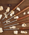 Badass Five Piece Wood Turning Lathe Chisel Set Featuring Rock Solid Tungsten Carbide Tips And Built Tough Square Stainless Handles on a wooden surface with shavings.