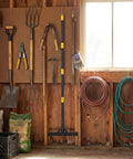 Heavy Duty Metal Bow Rake With 62 Inch Adjustable Handle Dual Sided Dethatching Rake hanging in a tool shed.