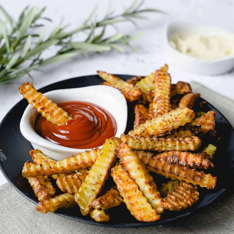 Triangle Crinkle Cutter - crispy crinkle-cut fries with red ketchup on a black plate