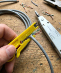 Person using integrated wire stripper on Cat6 cable with Pro Grade Impact Punch Down Tool And Integrated Wire Stripper RJ45 Crimping Kit.