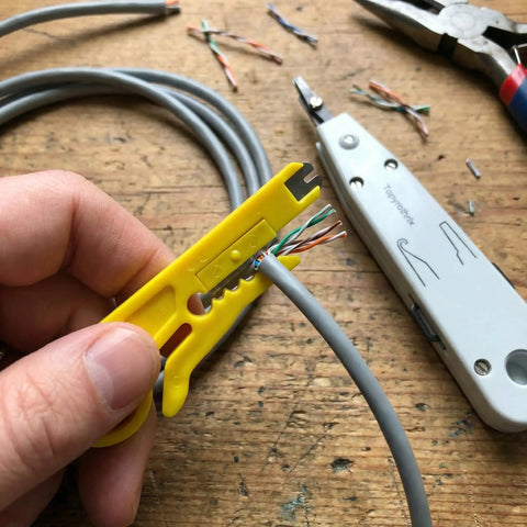 Person using integrated wire stripper on Cat6 cable with Pro Grade Impact Punch Down Tool And Integrated Wire Stripper RJ45 Crimping Kit.