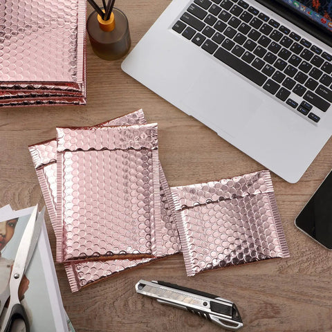 Rose Gold Metallic Bubble Mailers With Self Seal Adhesive, 50 Pack Padded Poly Mailers For Valentine Shipping displayed on a desk