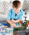 Boy in blue shirt exploring nature with Epic Compound Microscope Starter Kit For Kids Featuring 1200x Magnification With Dope Accessory Pack.