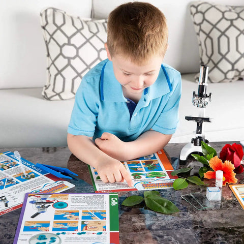 Boy in blue shirt exploring nature with Epic Compound Microscope Starter Kit For Kids Featuring 1200x Magnification With Dope Accessory Pack.
