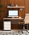 Modern home office setup with a wooden desk, rolling chair, computer monitor, and shelf with plants and books for productivity.