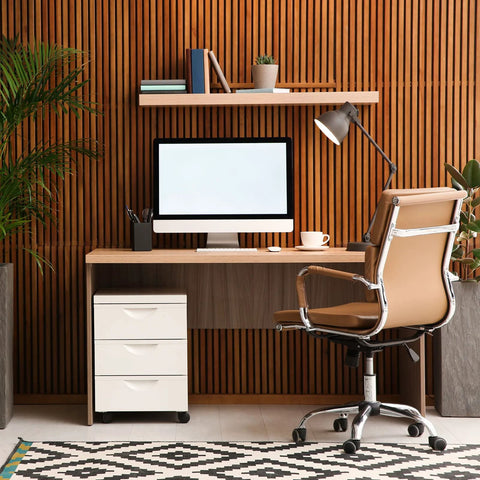 Modern home office setup with a wooden desk, rolling chair, computer monitor, and shelf with plants and books for productivity.