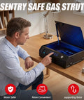 Man using a black safe with Sentry Safe branding and visible gas strut mechanism on a wooden desk