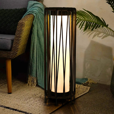 Outdoor Solar Floor Lamp With Rattan Trim And Steel Frame beside a chair, glowing warmly for cozy vibes on a patio